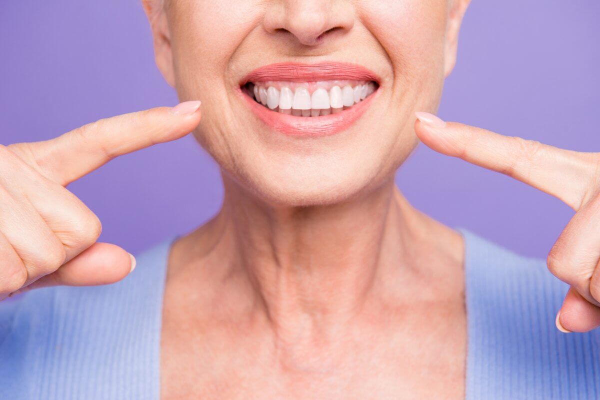 Woman Pointing To Her Smile And Healthy Teeth